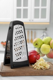 Grater and fresh ripe apples on white table in kitchen