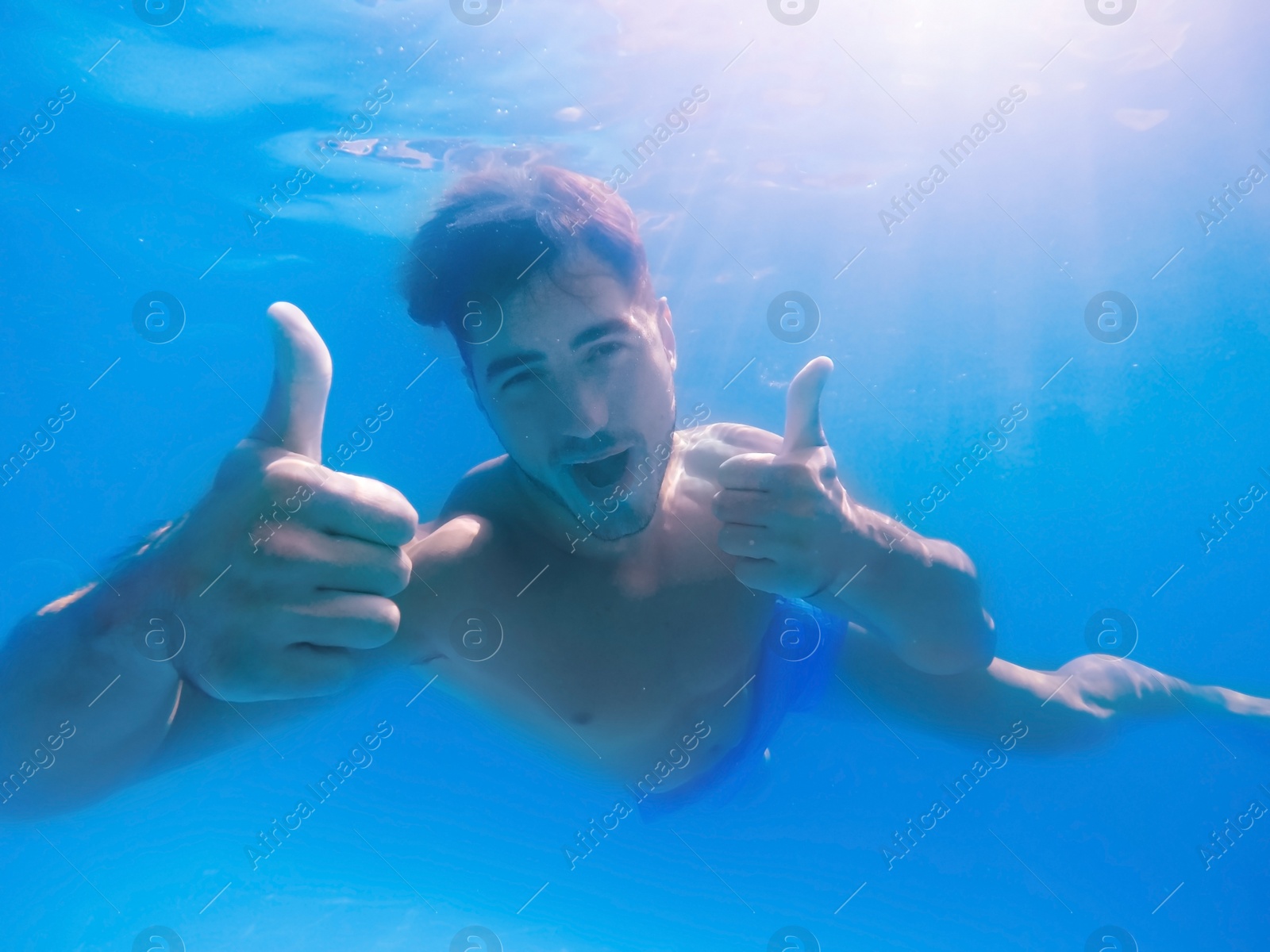 Photo of Handsome young man swimming in pool, underwater view