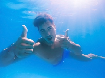 Handsome young man swimming in pool, underwater view