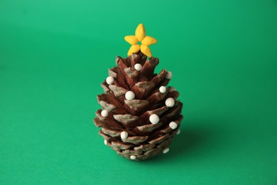 Photo of Christmas tree made from pine cone and plasticine on green background. Children's handmade ideas