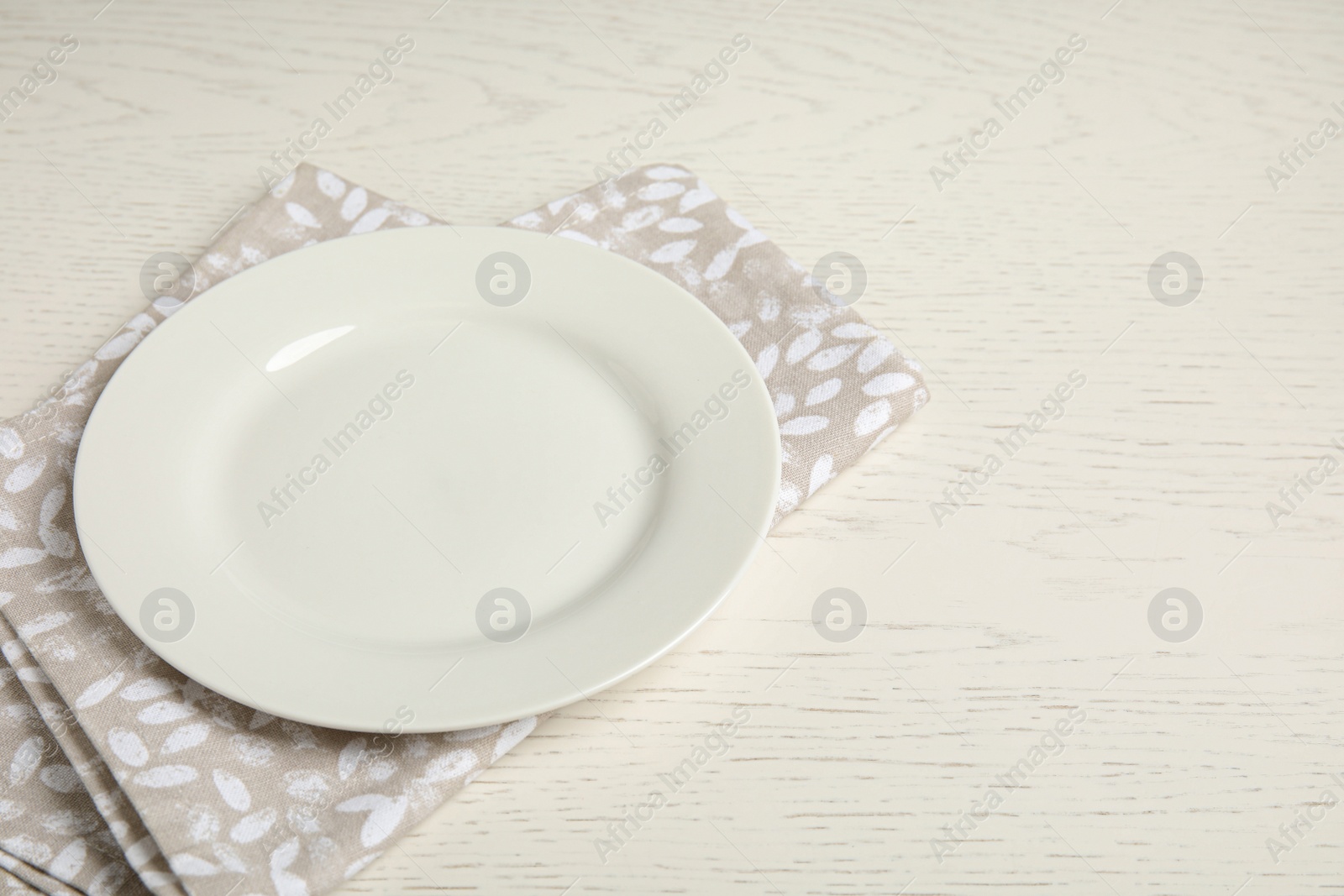 Photo of Empty plate and napkin on white wooden table