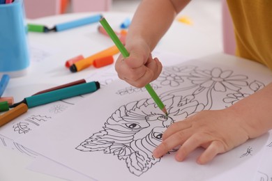 Photo of Child coloring drawing at table in room, closeup