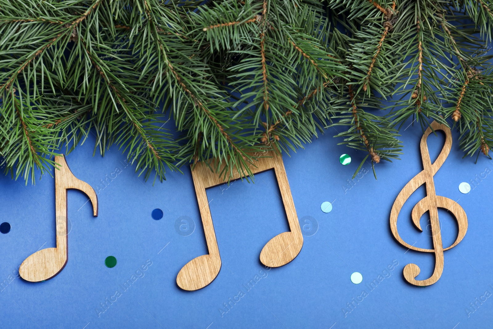 Photo of Fir tree branches with wooden music notes on blue background, flat lay. Christmas celebration