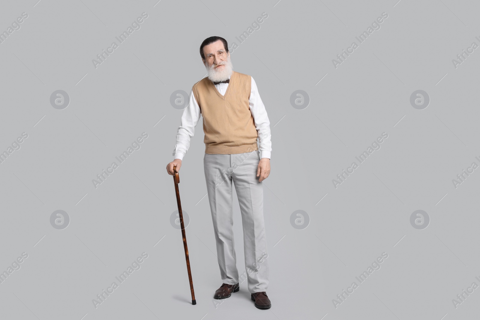 Photo of Senior man with walking cane on light gray background