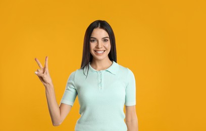 Photo of Woman showing number two with her hand on yellow background