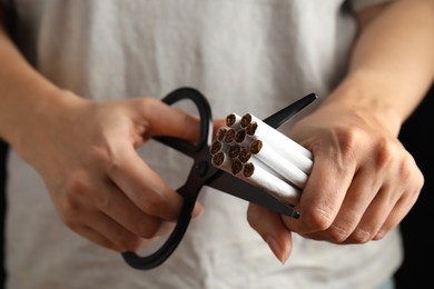 Photo of Woman cutting cigarettes, closeup. Quitting smoking concept