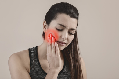 Image of Young woman suffering from toothache on beige background