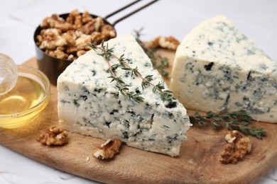 Photo of Tasty blue cheese with thyme, honey and walnuts on white table, closeup