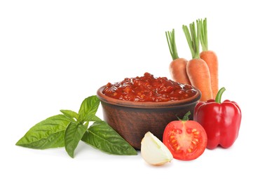 Delicious adjika sauce in bowl and ingredients on white background 