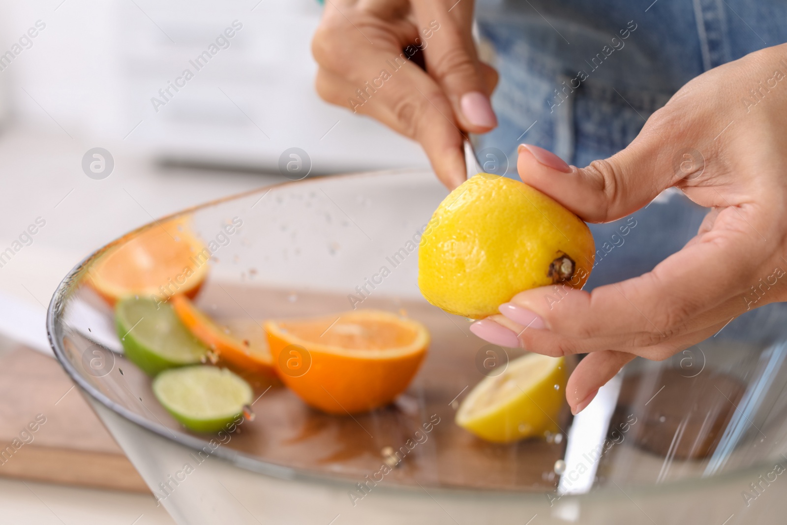 Photo of Young woman squeezing juice in bowl for lemonade on table, closeup. Natural detox drink