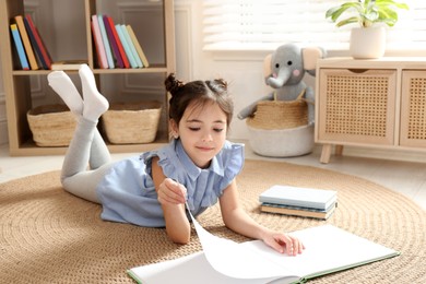 Little girl reading book on floor at home