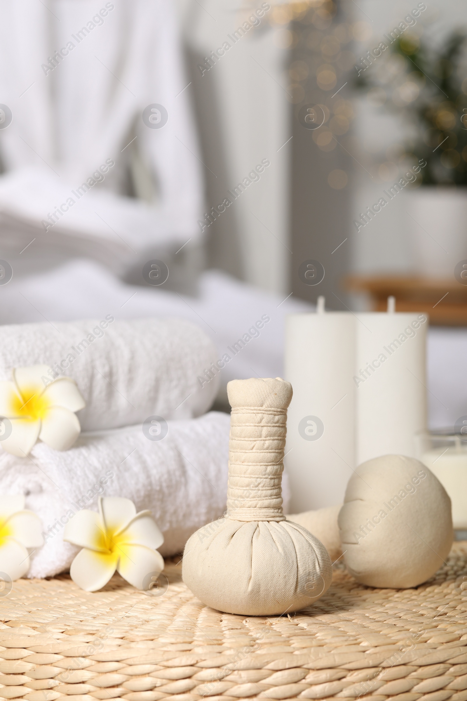 Photo of Herbal bags, candles, rolled towels and beautiful flowers on wicker surface indoors. Spa products