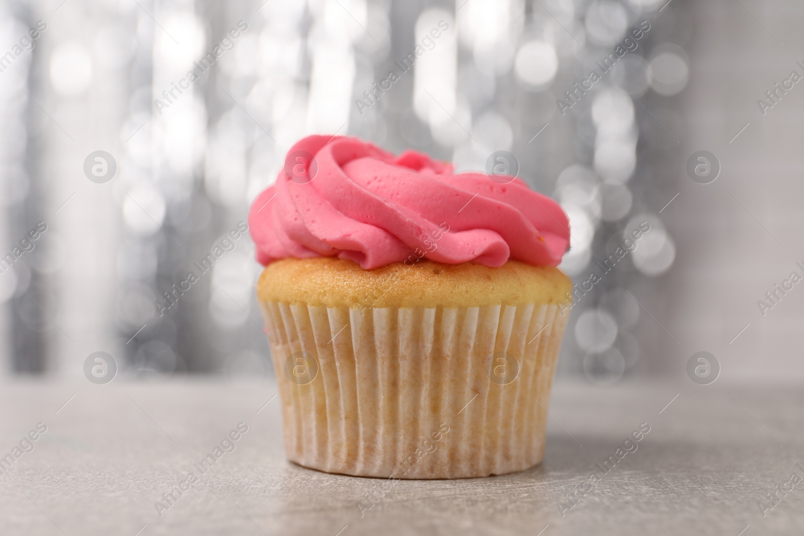 Photo of Delicious cupcake with bright cream on grey table, closeup