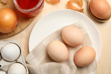 Photo of Easter eggs painted with natural food coloring and onion on wooden table, flat lay