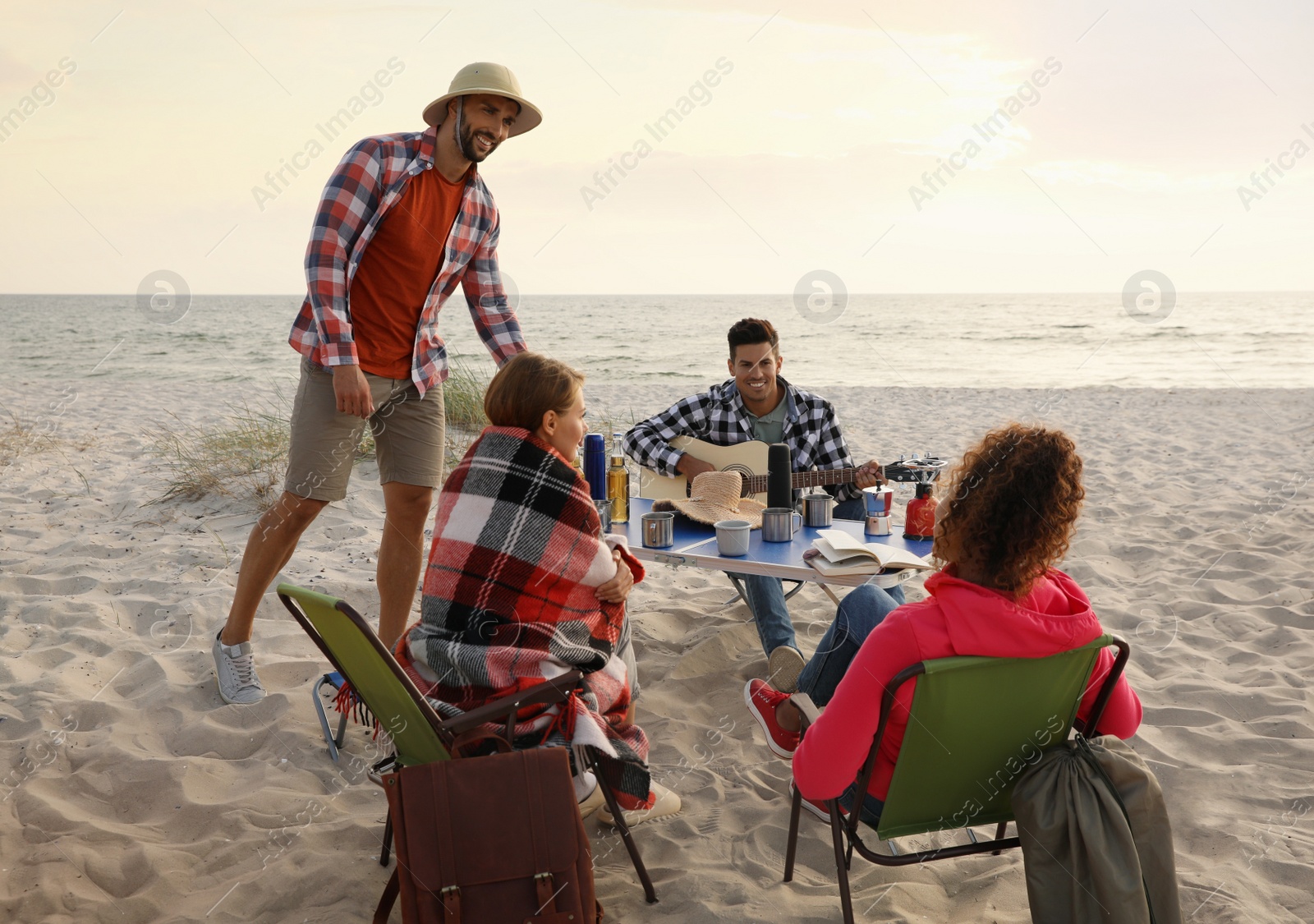 Photo of Friends resting on sandy coast. Beach camping