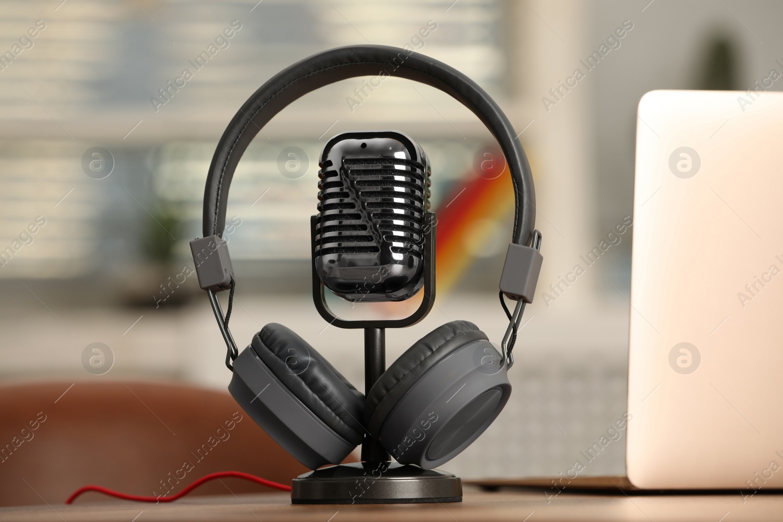 Photo of Microphone, modern headphones and laptop on table indoors