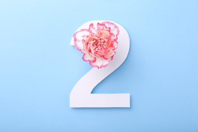 Paper number 2 and beautiful flower on light blue background, top view