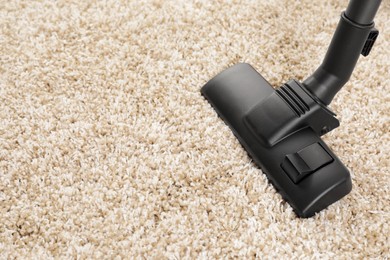 Photo of Hoovering carpet with modern vacuum cleaner indoors, closeup. Space for text