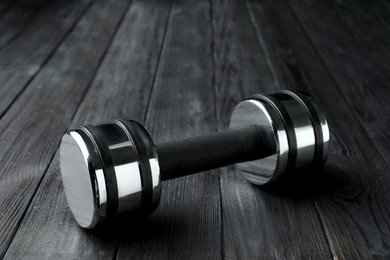 Photo of One metal dumbbell on black wooden table