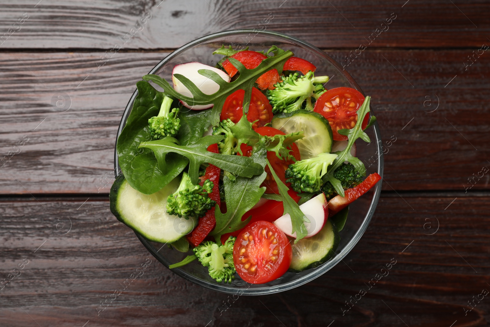 Photo of Tasty fresh vegetarian salad on dark wooden table, top view