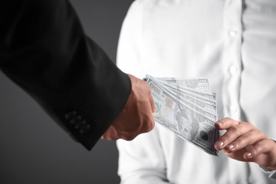 Man giving bribe money to woman on dark background, closeup