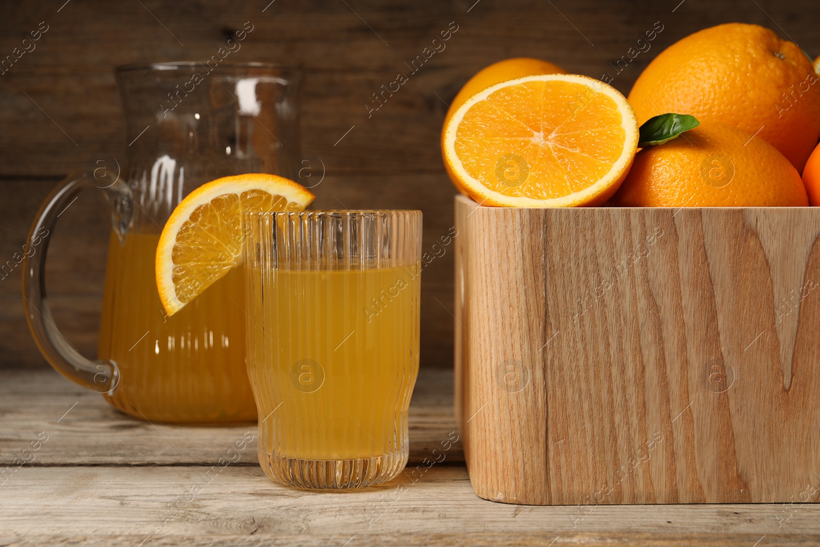 Photo of Many ripe oranges and fresh juice on wooden table