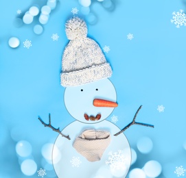 Image of Snowman with hat and scarf on light blue background, flat lay. Bokeh effect 