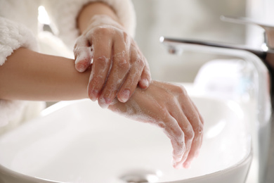 Photo of Woman washing hands with soap over sink in bathroom, closeup