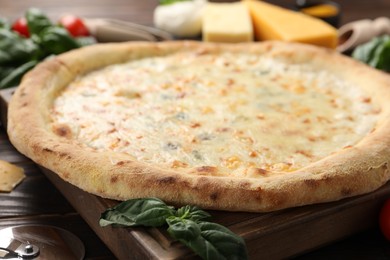 Photo of Delicious cheese pizza and basil on wooden board, closeup