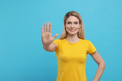 Woman giving high five on light blue background. Space for text
