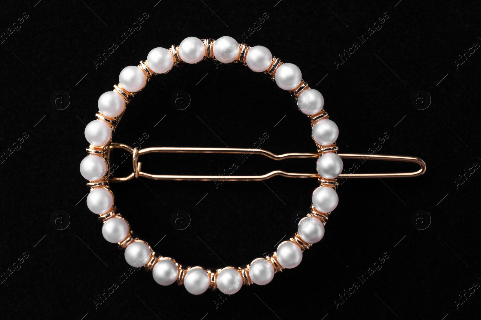 Photo of Elegant pearl hair clip on black background, top view
