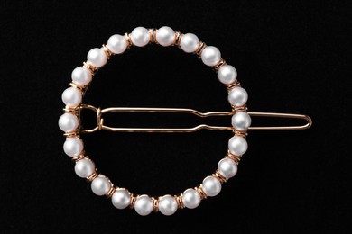 Elegant pearl hair clip on black background, top view