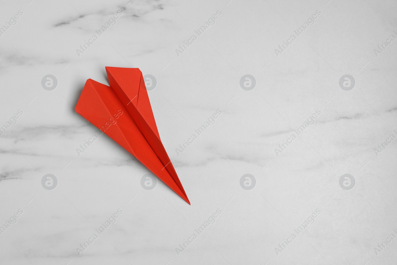 Photo of Handmade paper plane on white marble table, top view. Space for text