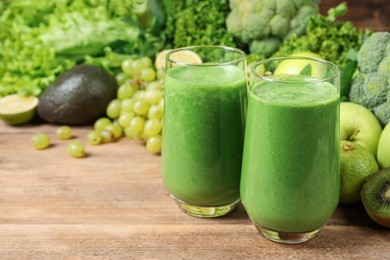 Photo of Glasses of fresh green smoothie and ingredients on wooden table, space for text