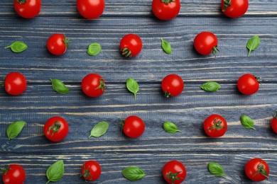 Flat lay composition with fresh cherry tomatoes and basil leaves on blue wooden table