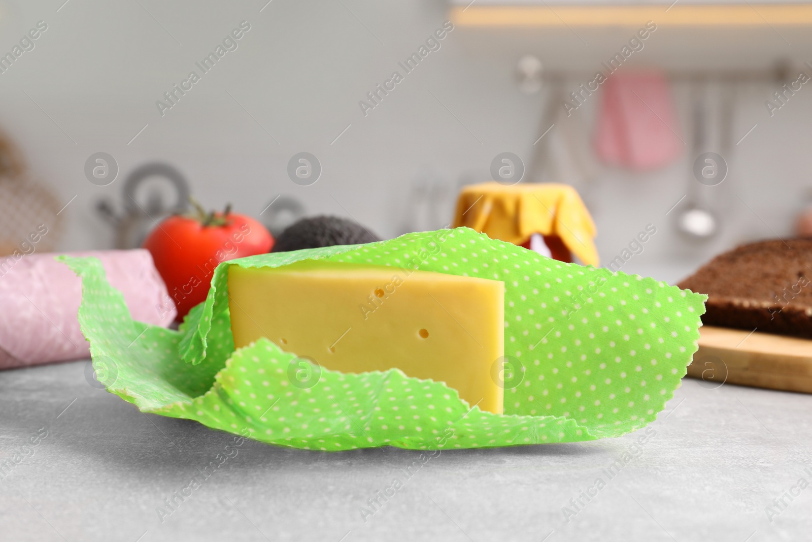 Photo of Piece of cheese in beeswax food wrap on light grey table