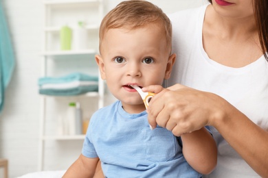 Woman and her son with toothbrush on blurred background