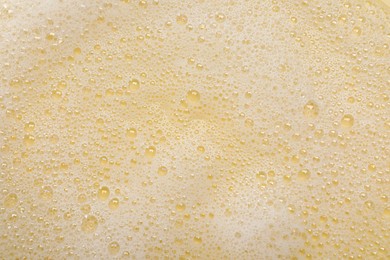White washing foam on yellow background, top view