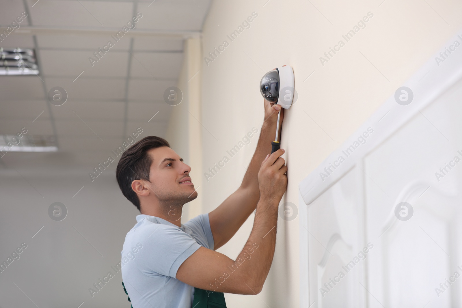 Photo of Technician installing CCTV camera on wall indoors