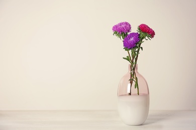 Photo of Beautiful flowers in vase and space for text on light background. Element of interior design