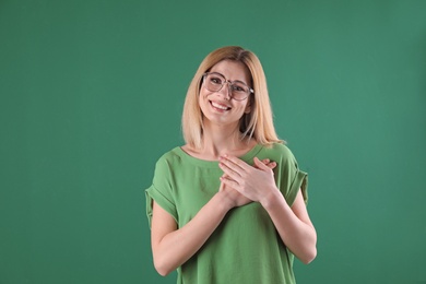 Photo of Portrait of woman holding hands near heart on color background