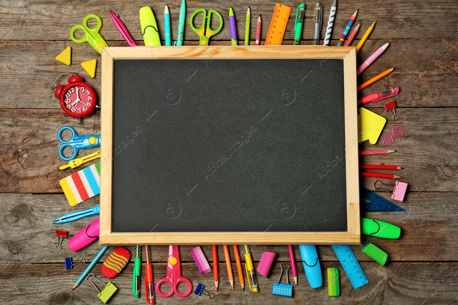 Photo of Flat lay composition with different school stationery and small chalkboard on wooden background