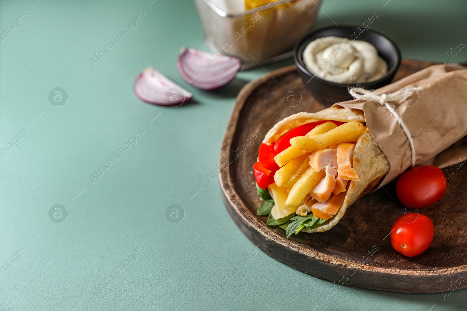 Photo of Delicious pita wrap with chicken, french fries and pepper on light blue background, space for text