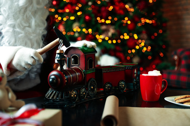 Photo of Santa Claus making new toy for Christmas in workshop, closeup