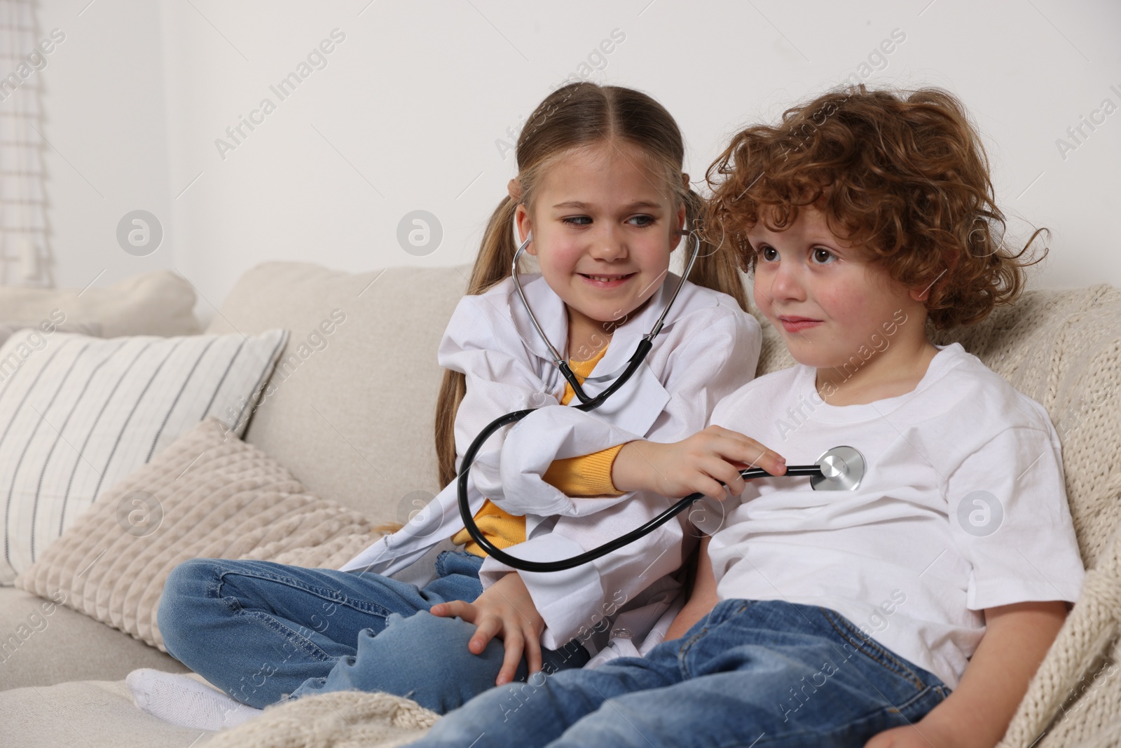 Photo of Little girl playing doctor with her friend at home