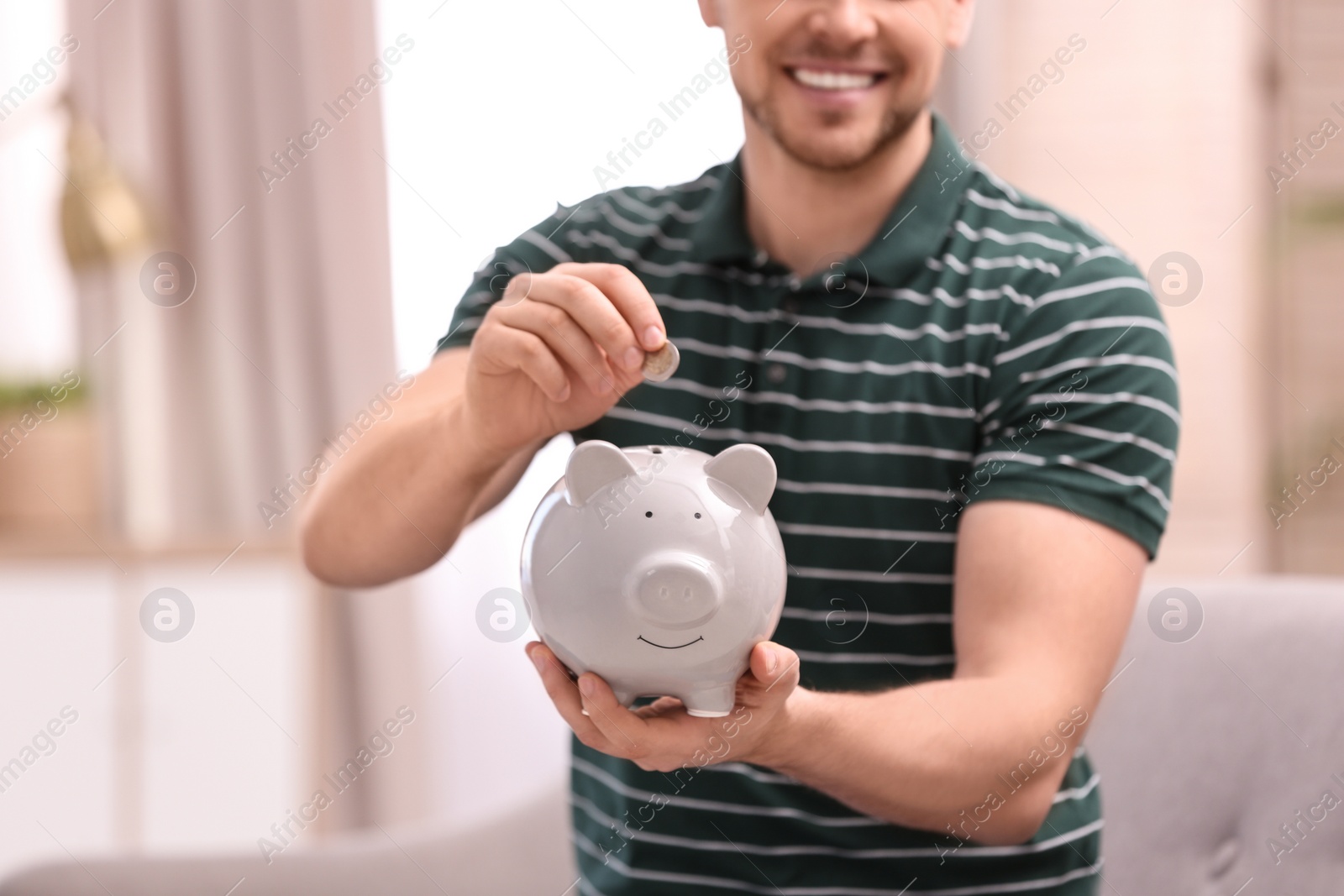 Photo of Man with piggy bank and money at home