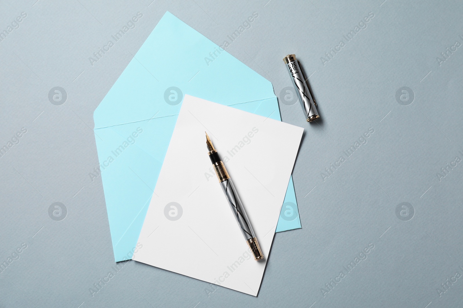 Photo of Blank sheet of paper, letter envelope and pen on grey background, top view