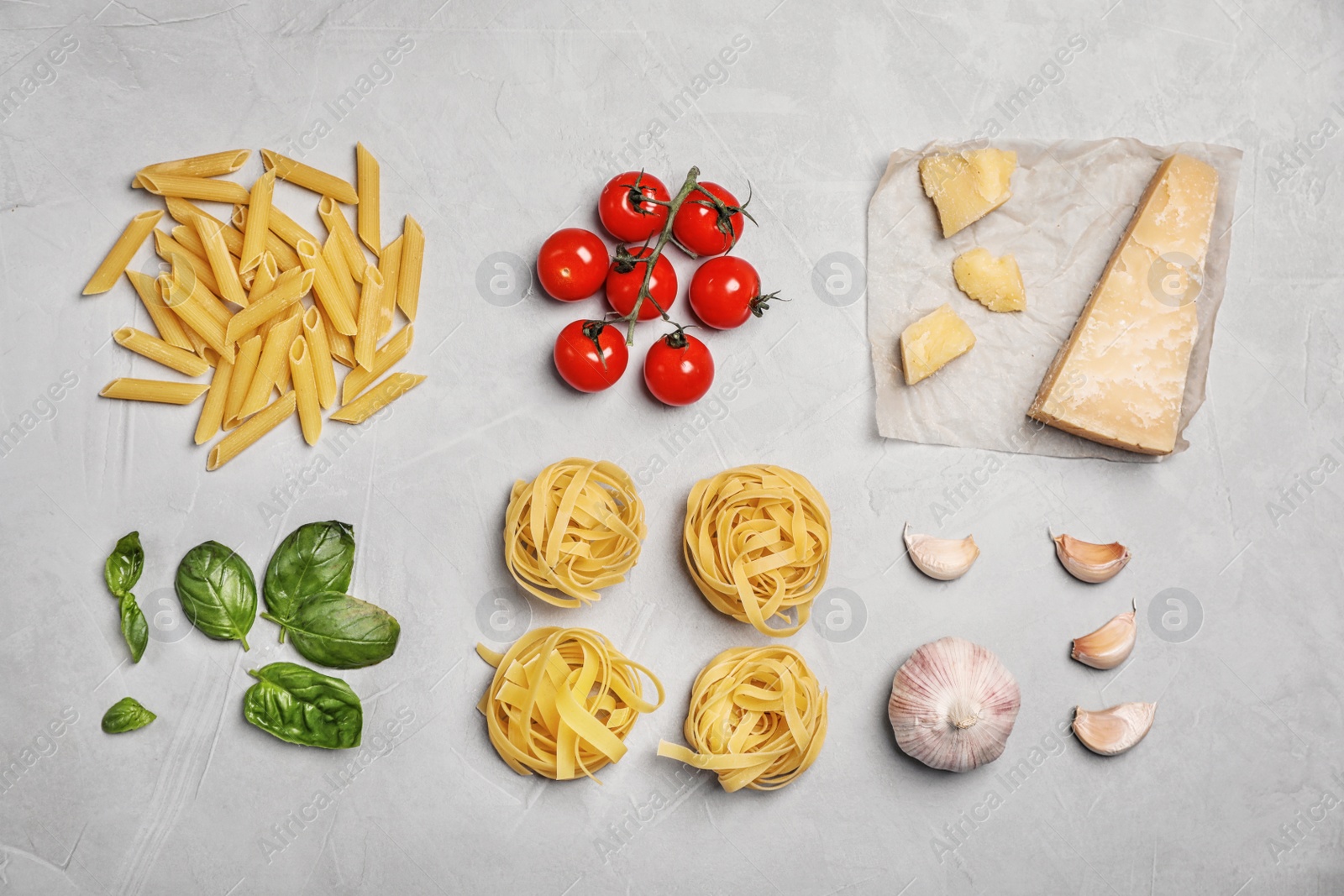 Photo of Flat lay composition with uncooked pasta and products on grey table