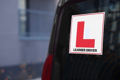 L-plate on car outdoors, closeup with space for text. Driving school