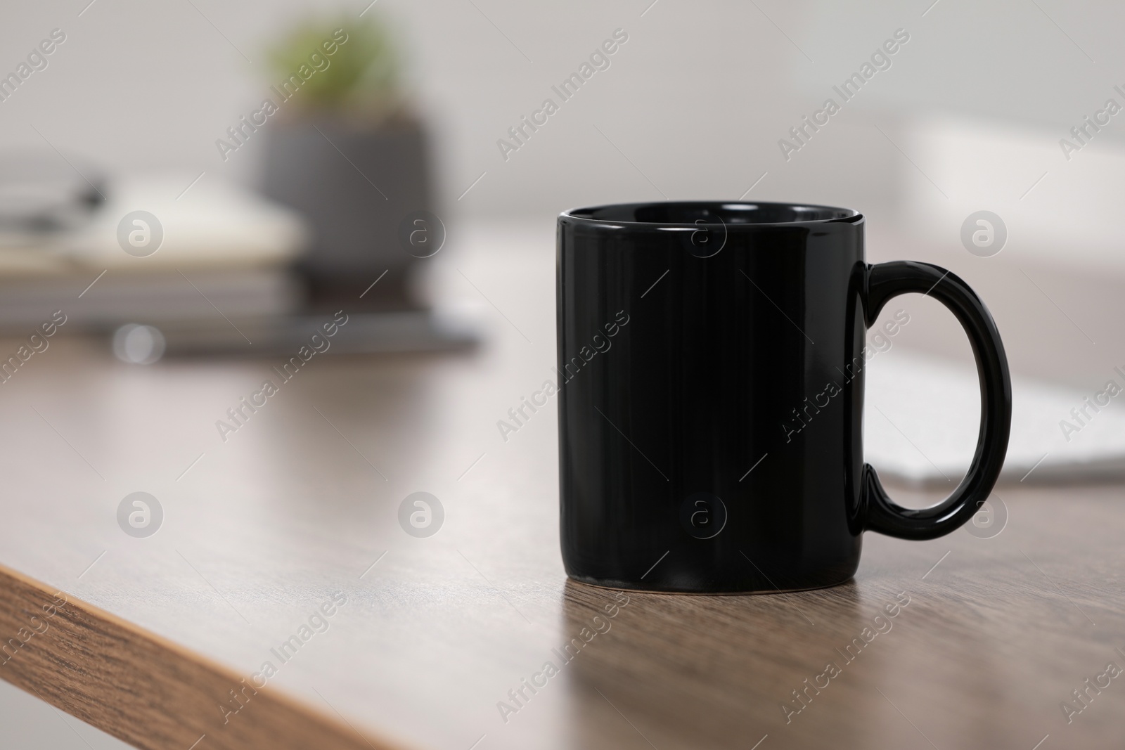 Photo of Black ceramic mug on wooden table at workplace. Space for text